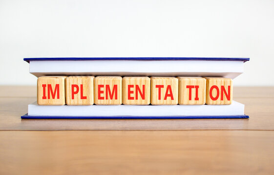 Implementation word symbol. Concept word Implementation on beautiful wooden blocks in book. Beautiful wooden table white background. Business implementation word concept. Copy space.