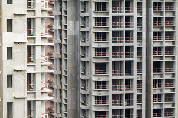Fototapeta premium Apartment or office tall building under construction. Brick walls, glass windows, scaffolding and concrete support pillars