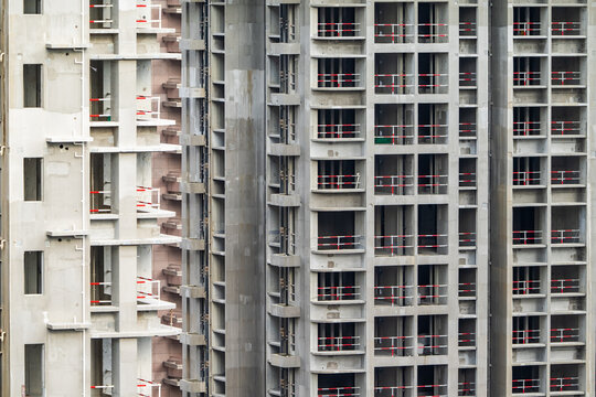 Apartment or office tall building under construction. Brick walls, glass windows, scaffolding and concrete support pillars