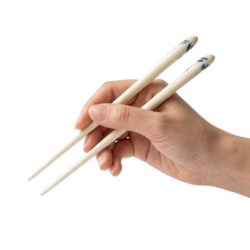 Primo piano di una mano che tiene correttamente un paio di bacchette di ceramica bianca con decorazioni blu, isolato su sfondo bianco per concetti di cucina asiatica e ristorazione.