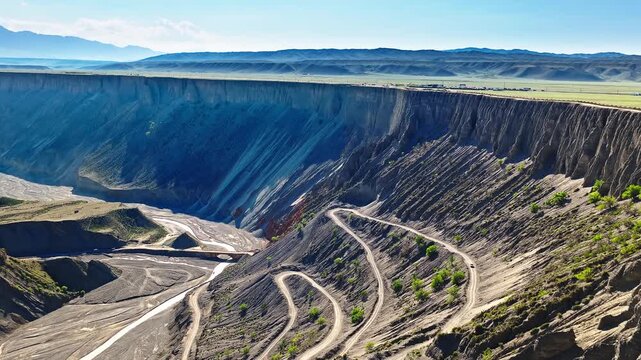 Aerial view of a winding switchback road leading down a deep canyon cliff in Anjihai Grand Canyon, Xinjiang, China
