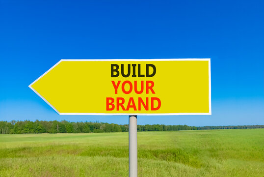 Build your brand words symbol. Concept words Build your brand on beautiful yellow road sign. Beautiful blue sky green grass background. Business and build your brand concept. Copy space.
