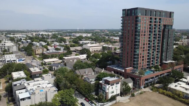 Towering brick residential highrise overlooks private pool terrace near Welborn Street, Dallas. Paved roadways connect diverse low rise housing units smoothly, DFW Metroplex, Texas