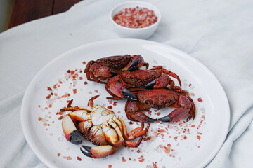 Overhead view of cooked crabs and sea salt on a white plate, nutritious seafood food, healthy lifestyle and balanced diet concept © svittlana