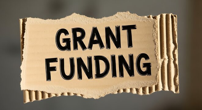 Torn Cardboard Sign Displaying Grant Funding Text on Neutral Blurred Background