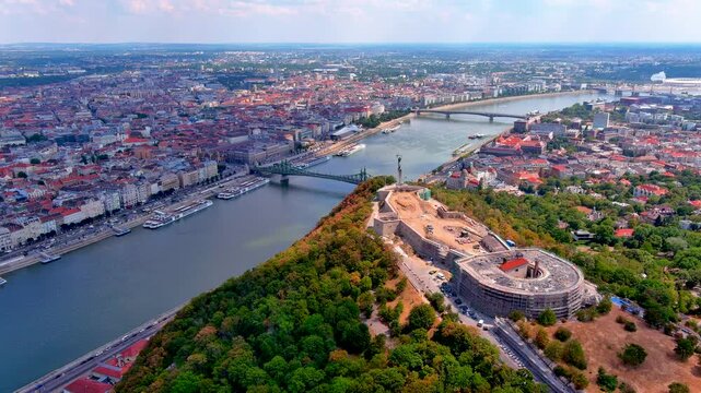 Aerial drone view of the Danube River with Gellert Hill, the Citadella under renovation, the Liberty Statue, Liberty Bridge and the Pest cityscape, Budapest, Hungary, in summer.