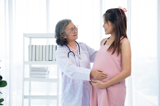 A healthcare professional in a white coat gently touches the abdomen of a pregnant woman during consultation. The photo conveys care, wellness, and trust, highlighting health, support, and positivity.