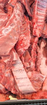 pile of raw. fresh pork ribs. featuring exposed bone structure and light pinkish-red meat with intercostal muscle tissue.
