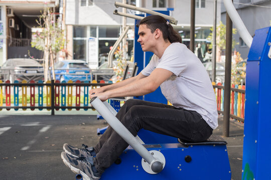 A man works out on gym equipment in an outdoor park.