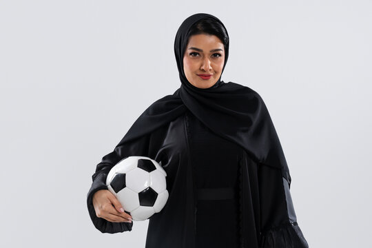 Muslim arab woman wearing traditional abaya holding soccer ball in studio
