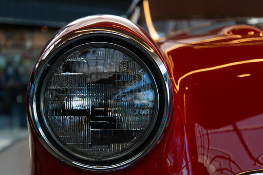 Close-Up Detail of Round Headlight on Red Vintage Classic Car