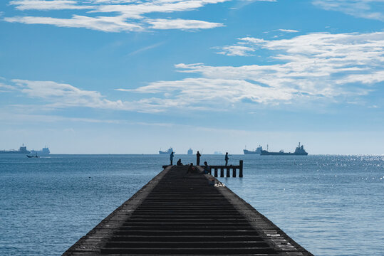 Long coastal pier extending toward the horizon over calm blue sea at Teluk Penyu Beach in Cilacap, Central Java, Indonesia