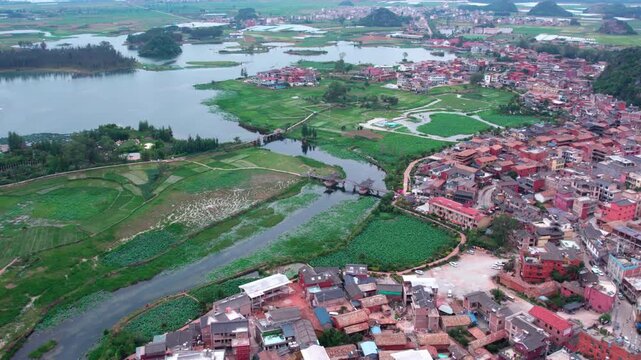 An aerial perspective shows a lakeside village adjacent to wetland and agricultural areas, with waterways and bridges connecting the settlement.