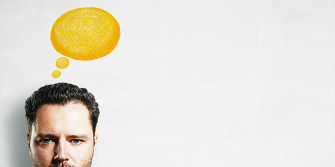Thoughtful man with yellow hand-drawn thought bubble on clean white background, bright copy space...