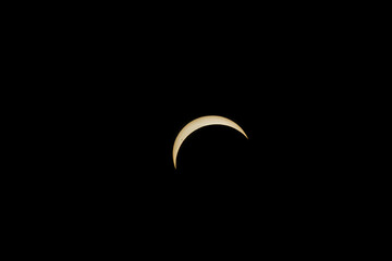 Partial solar eclipse showing a bright golden crescent in black sky © AdobeTim82