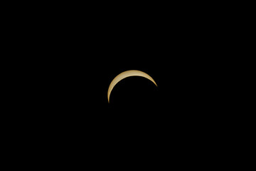 Partial solar eclipse showing a bright golden crescent in black sky © AdobeTim82