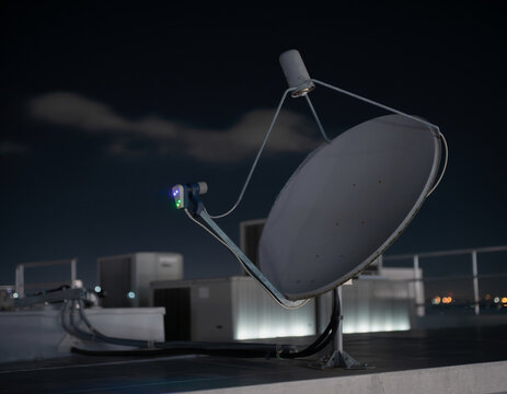 Nighttime medium shot highlighting a satellite dish with glowing LED indicators, while the rest of the installations are softly out of focus under a dark sky.