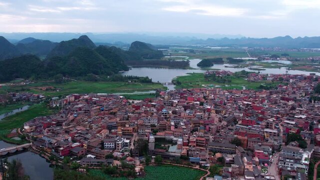 An aerial view of a riverside town surrounded by green mountains and water landscapes.