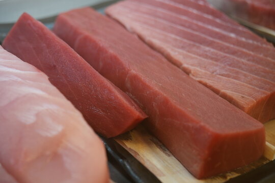 Fresh raw tuna fillets displayed closely in a market.