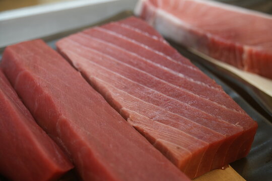Fresh raw tuna blocks displayed closely in a market.