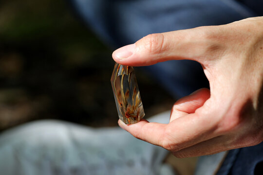 Hands holding a healing crystal with golden inclusions