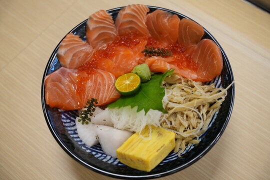 A fresh japanese salmon and ikura rice bowl served with sides.