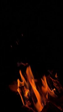 Subtle dark orange fire flame flicking gently in pitch black environment with copy space.