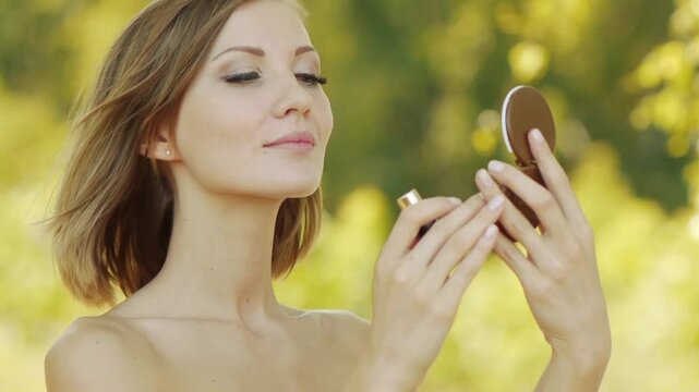 Young beautiful woman puts lipstick on lips