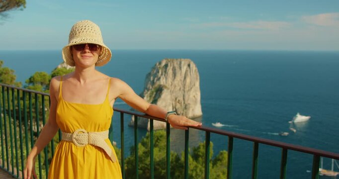 Tourist in yellow sundress by Capri cliffs and yachts on clear summer day
