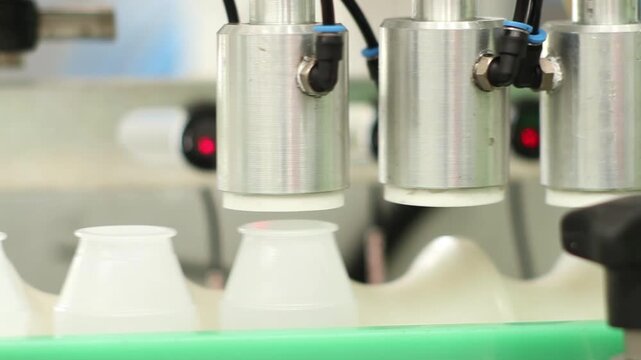 Automated filling machine nozzles on factory assembly line