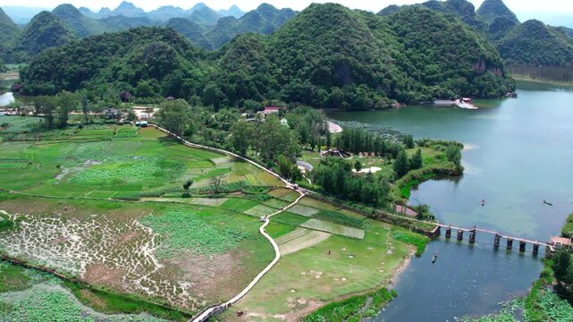 A serene karst landscape with lakes, traditional bridges, farmland and lush green hills.
