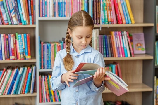 First grader choosing books and reading in school library