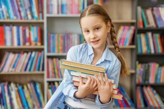 Student carrying stack of books in library