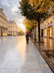 Fototapeta premium Person with Umbrella Walks on Wet Autumn City Street at Sunrise