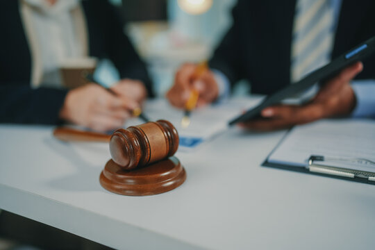 Gavel on table with lawyers reviewing legal documents