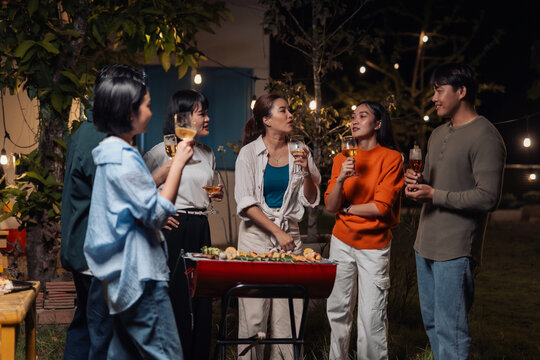 Friends enjoying backyard barbecue party at night