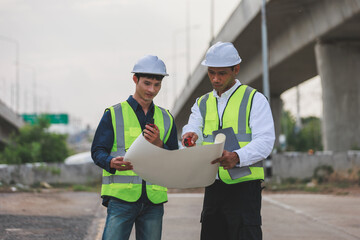 Engineers inspecting construction site plans under overpass © Crystal