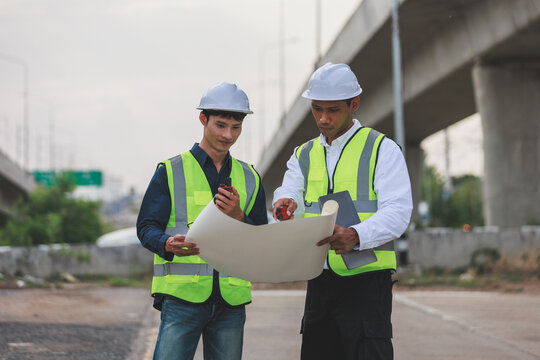 Engineers inspecting construction site plans under overpass