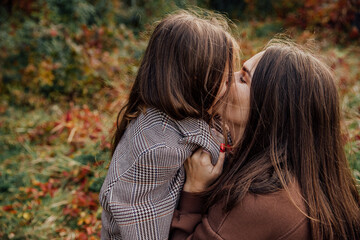 Fototapeta premium Mother and daughter share a tender moment in an autumn setting embracing the warmth of family love.