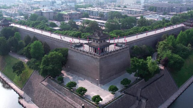 Aerial view of a historic city wall corner tower, flanked by a moat and surrounded by green urban landscape.