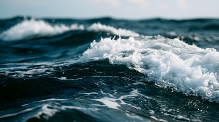 Naklejka premium Foamy ocean waves roll across deep blue water under soft natural light capturing the dynamic motion of the sea surface