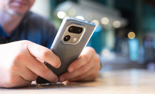 Man uses mobile device to browse internet at cafe during the daytime