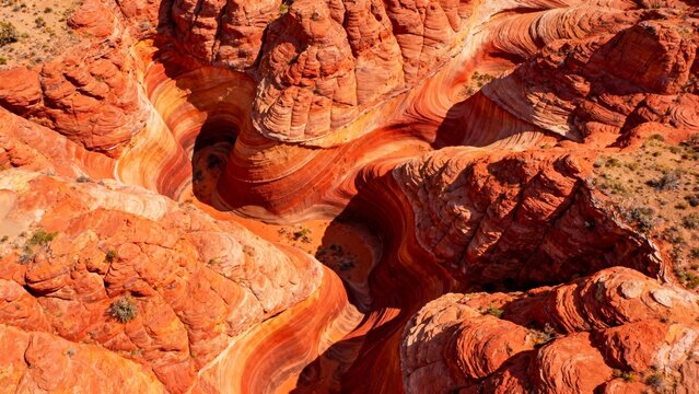 Aerial view of vibrant red sandstone formations with intricate wave-like patterns in a desert landscape