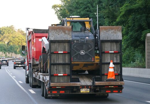 Pennsylvania, U.S.A - Jul 11, 2026 - A flatbed trailer transporting a John Deere front loader on the highway interstate 476 North