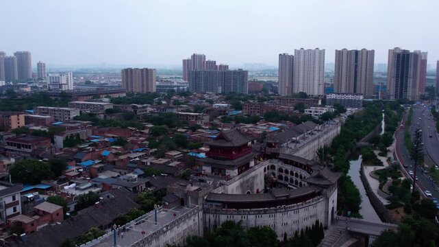 Aerial shot of an urban area combining traditional architecture and modern high-rise buildings, with roads and green spaces.