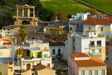 Fototapeta premium A high-angle view of the historic Arch of Hadrian in Athens, Greece, standing amidst the city's urban rooftops and residential buildings near the Acropolis.
