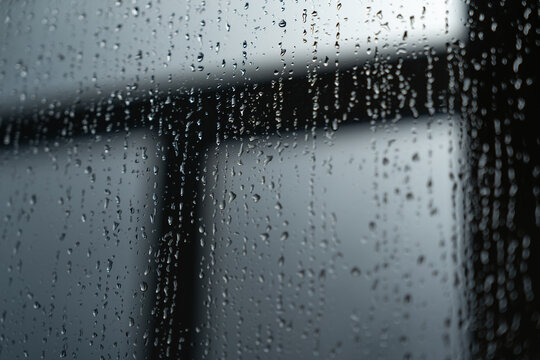 Raindrops on a window pane with a blurred background