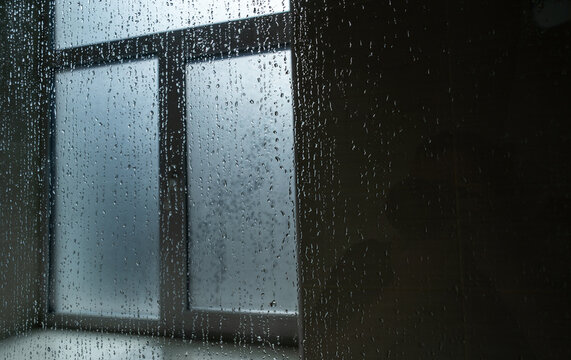 Raindrops on a glass window pane with a blurred interior view