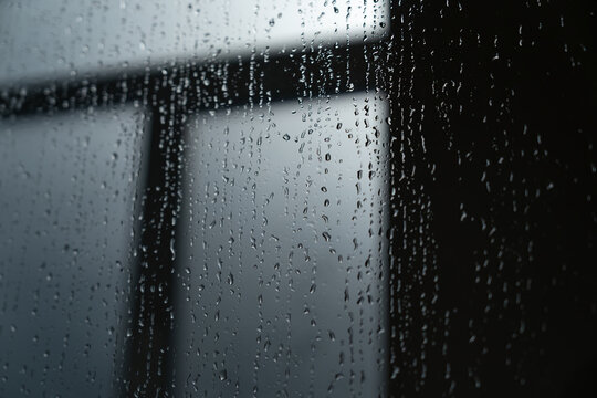 Raindrops on a window pane with a blurred background