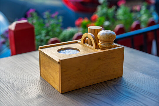Wooden condiment holder with salt and pepper shakers on a restaurant table